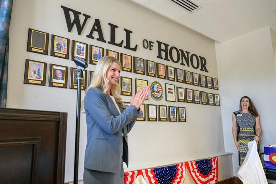 Congresswoman Brittany Pettersen stands in front of the wall of honor