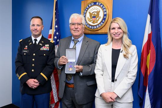 Congresswoman Brittany Pettersen stands with a constituent and a service member